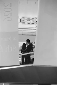 a black and white photo of a couple on an escalator