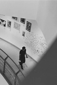 a black and white photo of a man walking down a stairwell